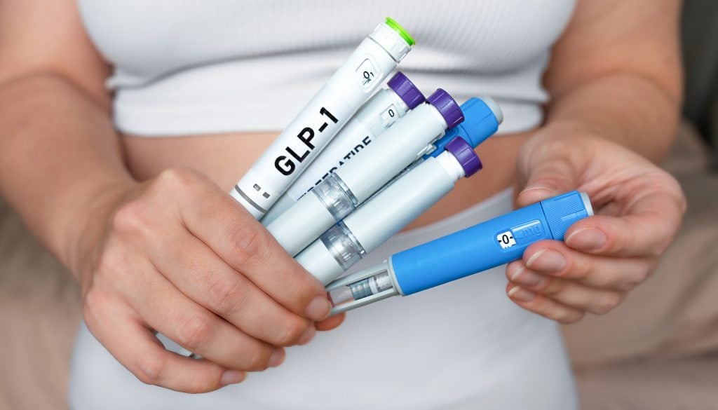Persoon houdt meerdere insuline spuiten voor diabetescontrole.