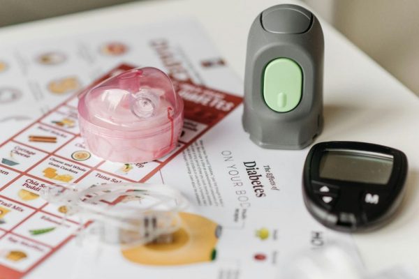Insulinepen, glucosemeter en diabetesinformatie op papier.